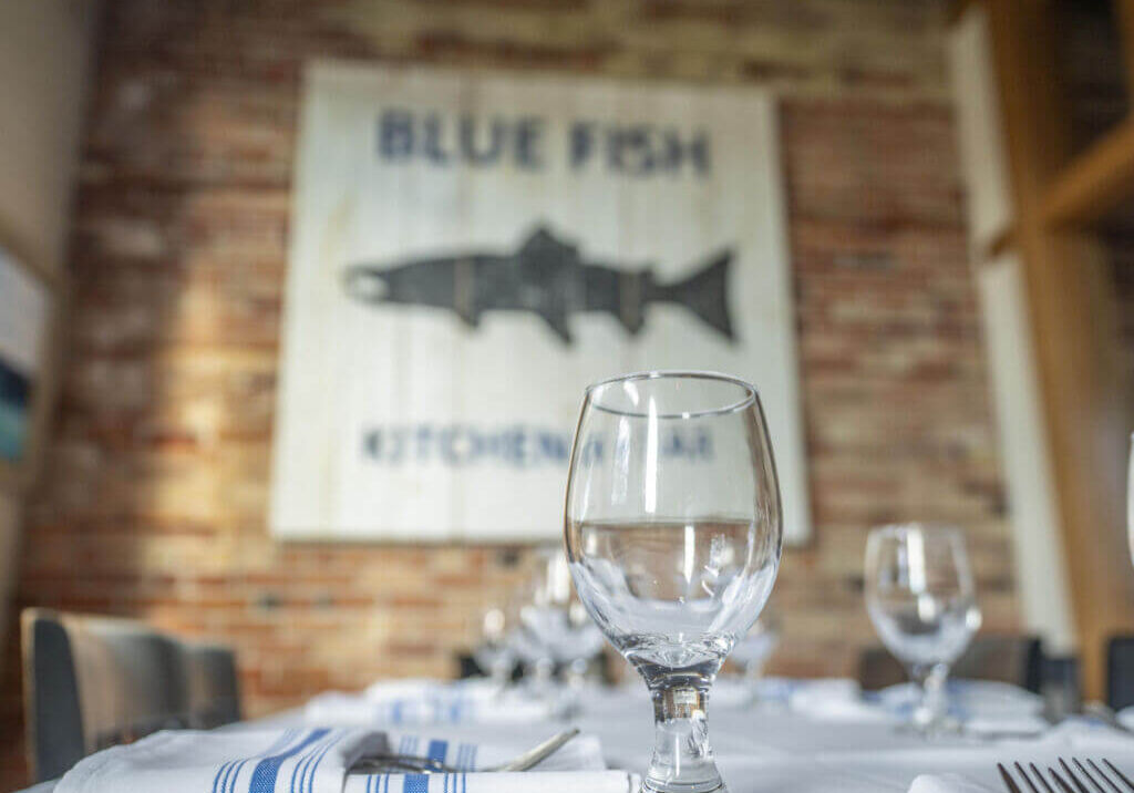 Elegant table setting at Bluefish Kitchen + Bar, with the restaurant's sign on the brick wall